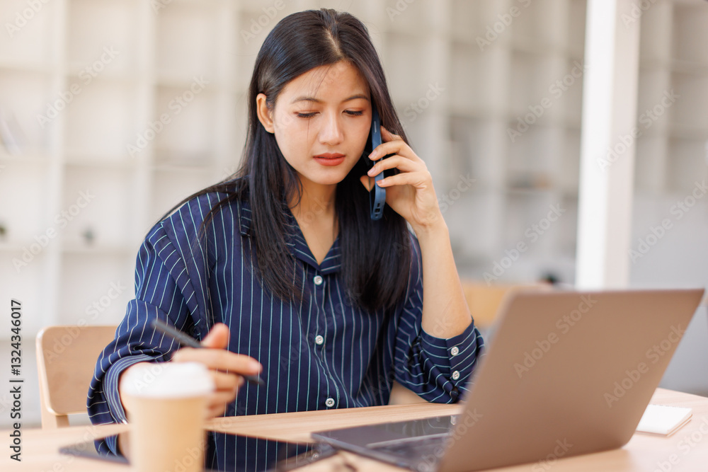 Attractive successful elderly business Asian woman in striped blouse working in modern office, making phone call to potential client, having nice conversation, sitting at desk in front of open laptop Attractive successful elderly business Asian woman in striped blouse working in modern office, making phone call to potential client, having nice conversation, sitting at desk in front of open laptop
