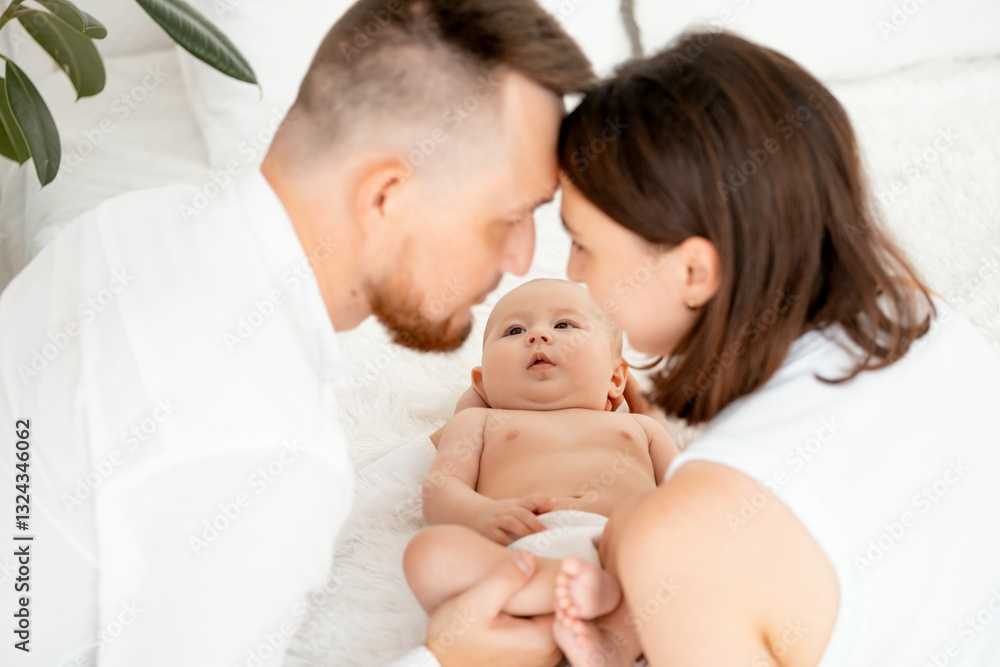 mom, dad with a baby, an international family, a Caucasian mom with an Asian husband and a baby in her arms in the bedroom gently hugs the baby holding in her arms, a place for text mom, dad with a baby, an international family, a Caucasian mom with an Asian husband and a baby in her arms in the bedroom gently hugs the baby holding in her arms, a place for text