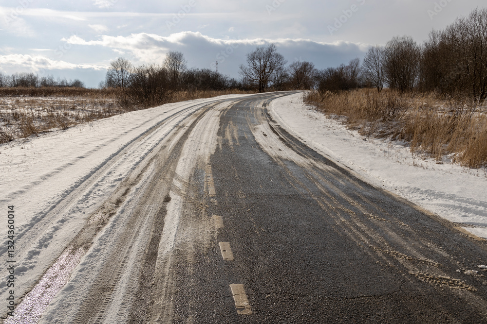 Road covered in snow and ice with a tire track in the middle Road covered in snow and ice with a tire track in the middle