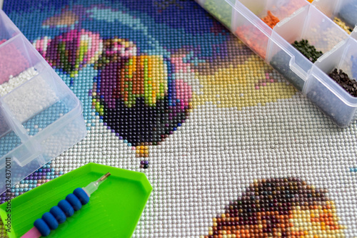 Close-up of a diamond painting and the tools needed to assemble it. Art therapy concept.