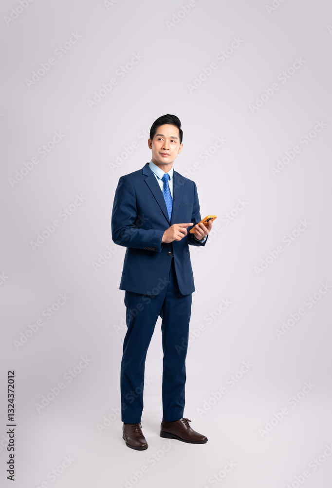 Full body image of Asian male businessman wearing a suit using phone and posing on a white background Full body image of Asian male businessman wearing a suit using phone and posing on a white background