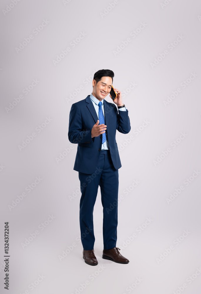 Full body image of Asian male businessman wearing a suit using phone and posing on a white background Full body image of Asian male businessman wearing a suit using phone and posing on a white background