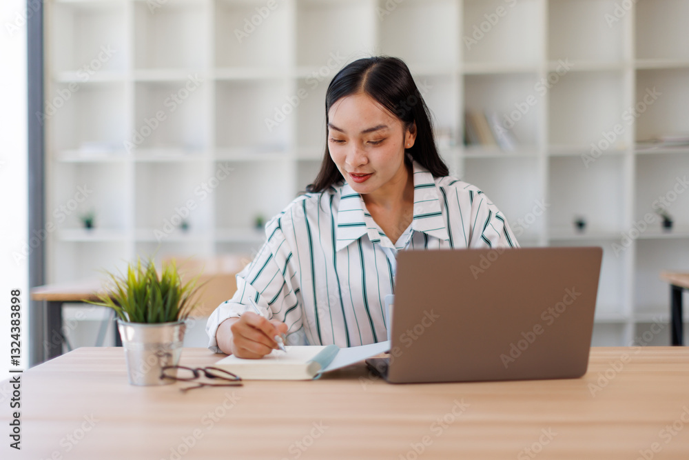 Smiling businesswoman working on laptop at desk in office, using technology and internet, while sitting comfortably at workplace. Smiling businesswoman working on laptop at desk in office, using technology and internet, while sitting comfortably at workplace.