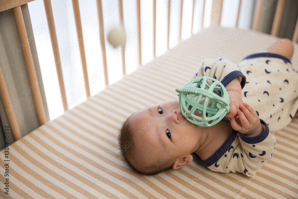 Adorable baby touching toy inside wooden crib
