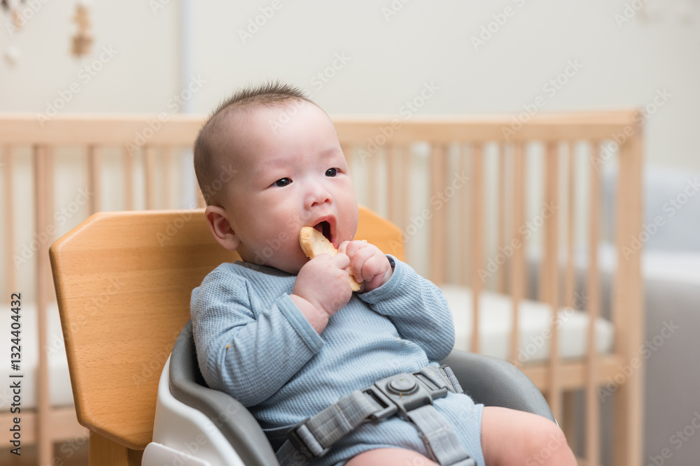 Little baby sitting in dining chair eating