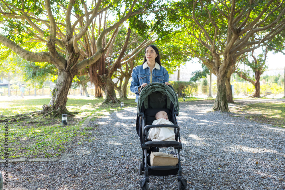 Happy mother strolling with baby in park