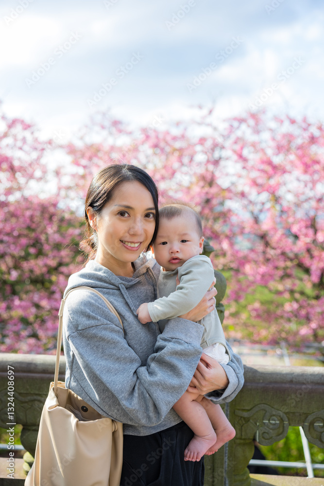 Young mother and baby enjoying cherry blossoms together