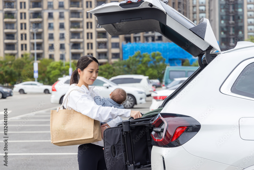 Mother holding baby while unloading car