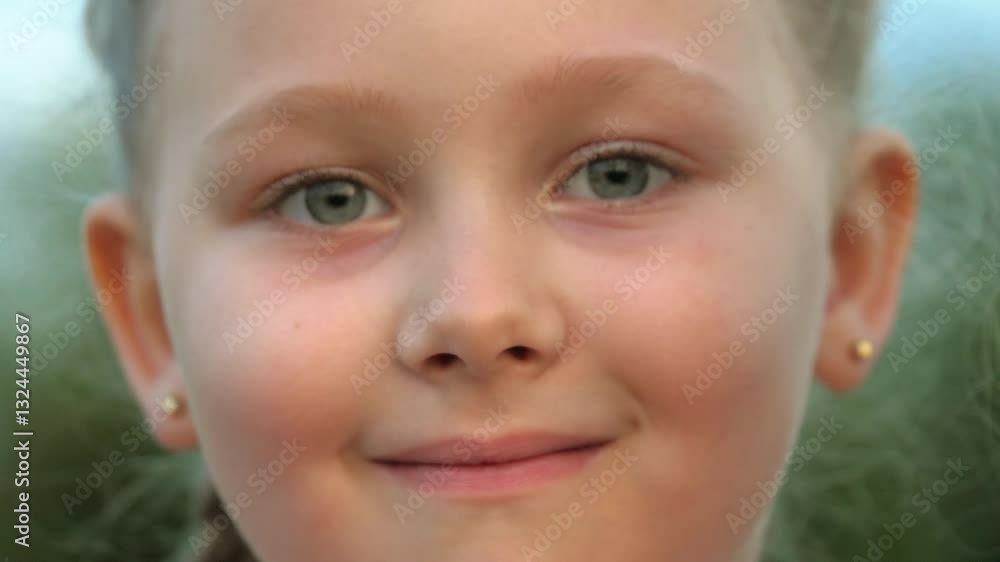 Upset little girl with grey eyes smiles to camera changing mood on blurred background closeup. Portrait of pretty preschooler girl smiles in green park. Adorable girl becomes happy and smiles outdoors Upset little girl with grey eyes smiles to camera changing mood on blurred background closeup. Portrait of pretty preschooler girl smiles in green park. Adorable girl becomes happy and smiles outdoors