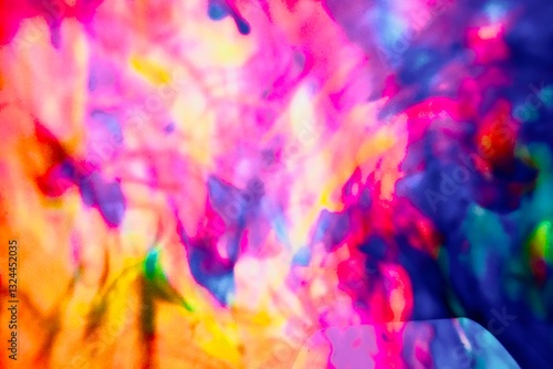 Abstract video with vibrant colors flowing with colored inks dispersed in water. The composition consists of shades of blue, red, green and yellow blending and swirling on a light background, creating