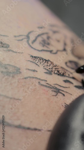 In this 4K vertical macro video at 60fps, a tattoo artist applies black ink to the skin with precision, focusing on every detail. The close-up shot highlights the intricate tattooing process.