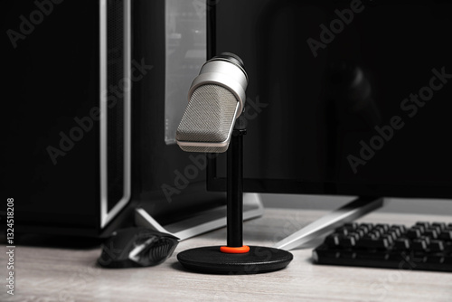Obraz na płótnie A professional condenser microphone on a desktop stand is set up in a modern gaming and recording workstation, surrounded by a computer monitor, keyboard, and gaming peripherals. w salonie