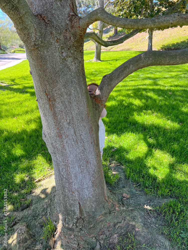 Cute little girl is playing around the grass and trees at the park