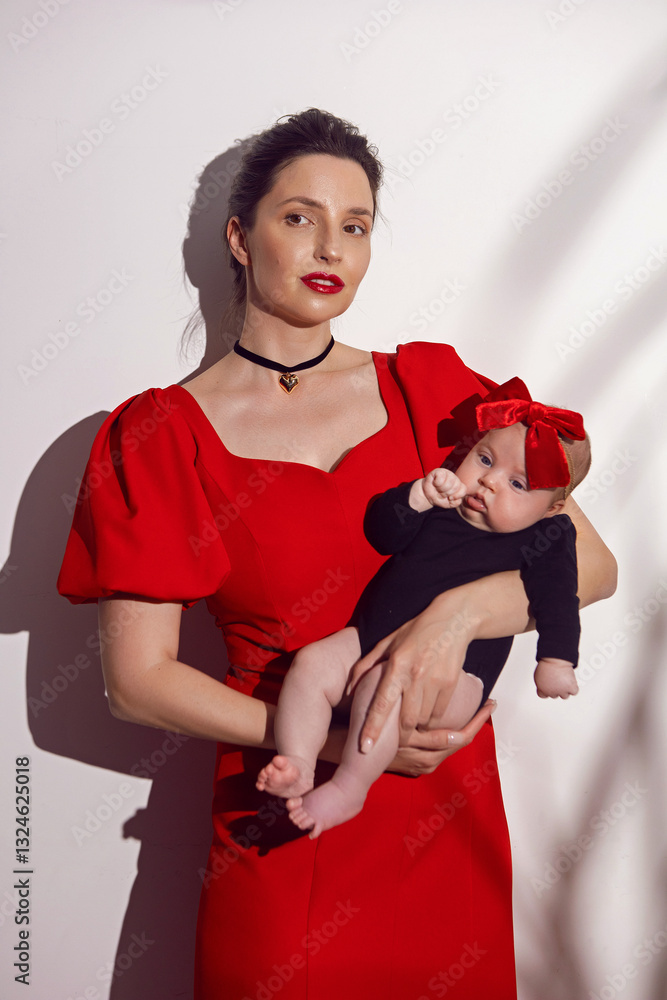 portrait a woman in a red dress holds a child at home on a white background with a shadow from a bush