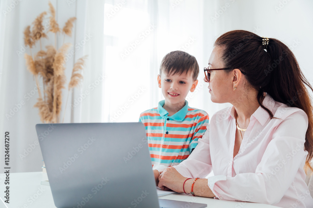 Female teacher teaching boy at desk with laptop Female teacher teaching boy at desk with laptop