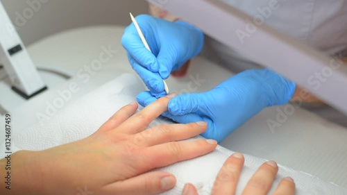 Manicure. A manicurist pushes back a client's cuticle with a wooden stick