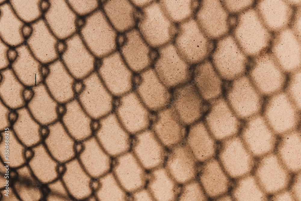 Shadow of a chain link fence on a textured sepia-toned wall
