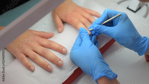 Manicure. A manicurist pushes back a client's cuticle with a wooden stick