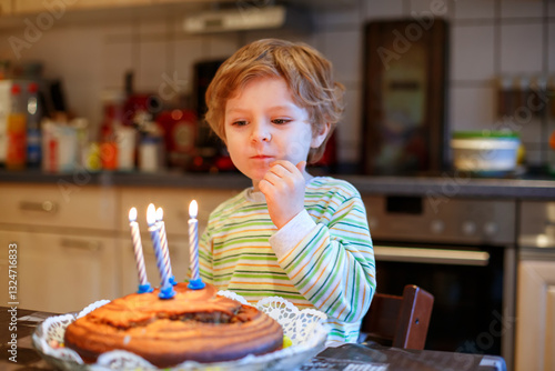 Adorable four year old boy celebrating his birthday and blowing off the candles on the cake, indoor. Happy child with big cake. photo