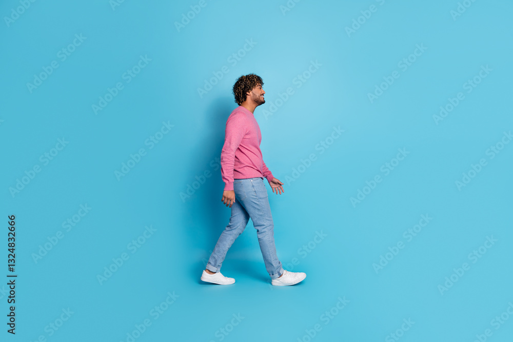 Young stylish male walking confidently in casual outfit against blue background Young stylish male walking confidently in casual outfit against blue background
