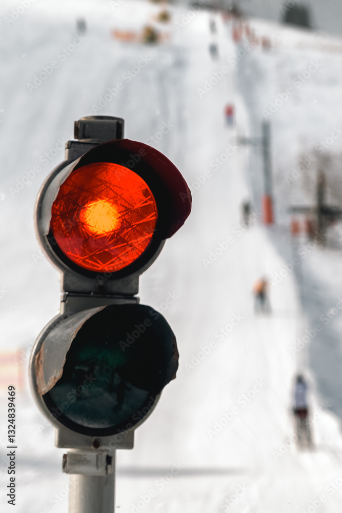 End of winter season. Red light on traffic light on slope with ski lift