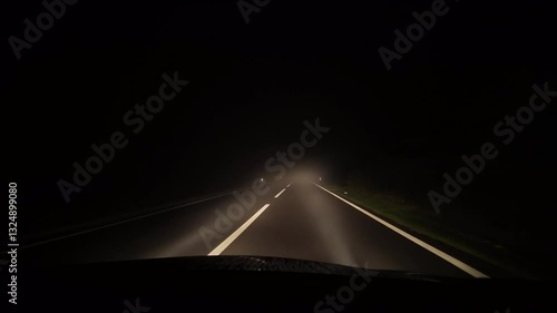 Driving in bad conditions on a foggy road at night. Front car windshield and white beam of lights. Winter weather concept, real time footage with evening lights. Nothing to see on the streets.