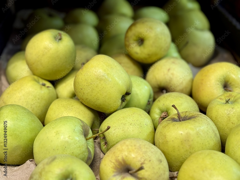 A mound of large green coloured apples in boxes is displayed in the window of the supermarket's vegetable stand, demonstrating organic, vegetarian and healthy food. Close-up A mound of large green coloured apples in boxes is displayed in the window of the supermarket's vegetable stand, demonstrating organic, vegetarian and healthy food. Close-up