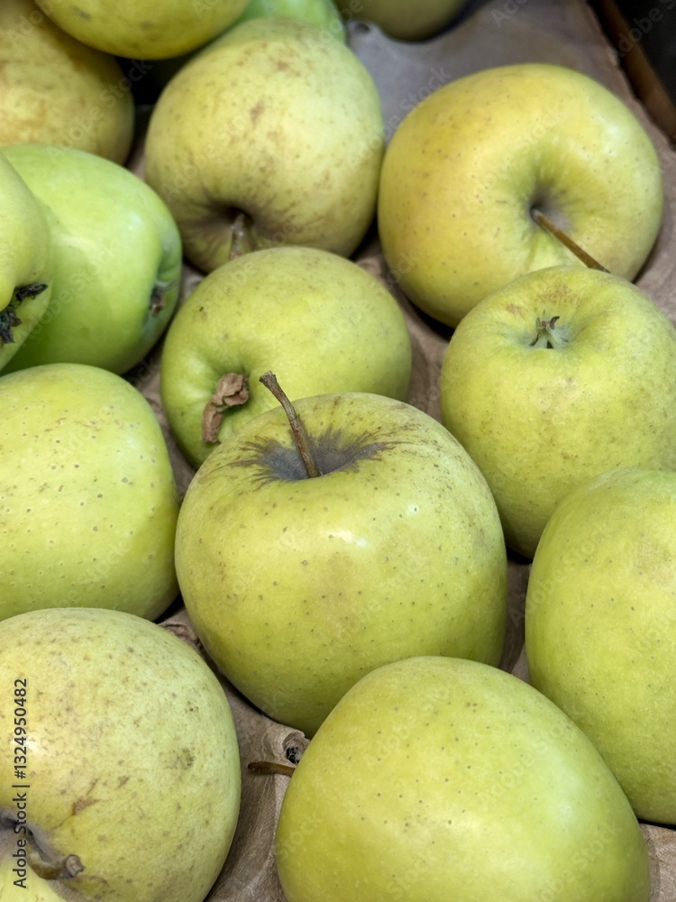 A mound of large green coloured apples in boxes is displayed in the window of the supermarket's vegetable stand, demonstrating organic, vegetarian and healthy food. Close-up A mound of large green coloured apples in boxes is displayed in the window of the supermarket's vegetable stand, demonstrating organic, vegetarian and healthy food. Close-up