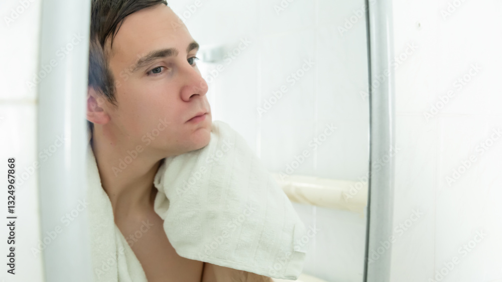 Young handsome man is wiping his face using a towel while looking into the mirror in bathroom. Young handsome man is wiping his face using a towel while looking into the mirror in bathroom.