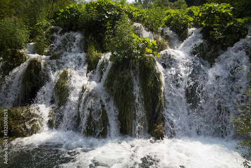 A tranquil view of the small waterfalls at Plitvice Lakes National Park, surrounded by lush greenery.