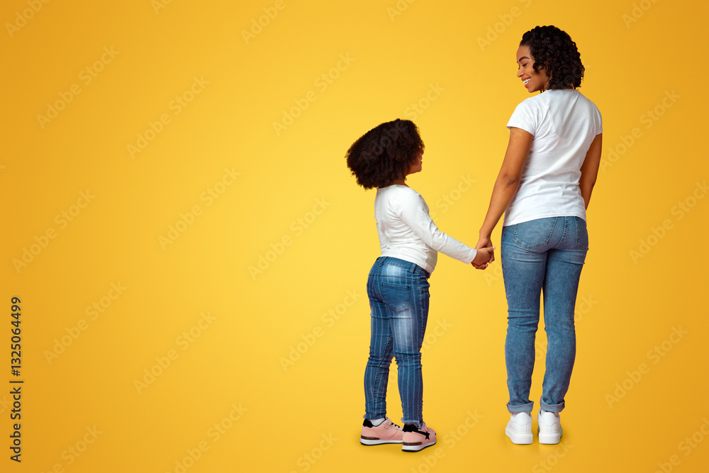 Rear View Of Loving Black Mom And Her Little Daughter Holding Hands And Smiling To Each Other, Standing On Pink Background In Studio, Full Length Rear View Of Loving Black Mom And Her Little Daughter Holding Hands And Smiling To Each Other, Standing On Pink Background In Studio, Full Length