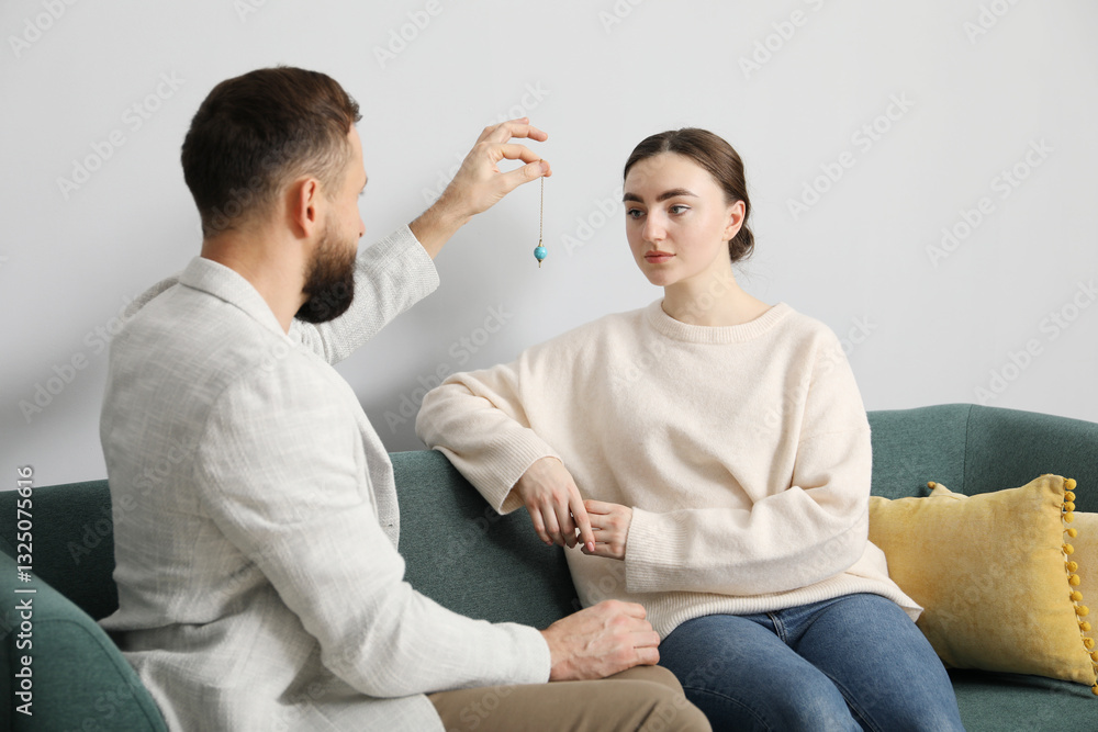 Psychologist using pendulum while working with patient during hypnosis session indoors