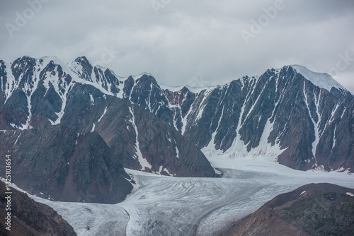 Dramatic overcast view to beautiful glacier tongue among rocky ridges and sha...