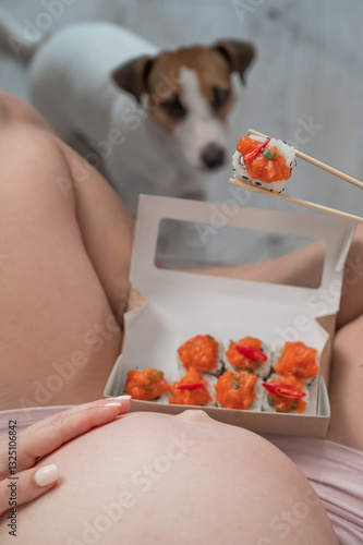 Konstfotografi A pregnant woman sits on the sofa and eats rolls