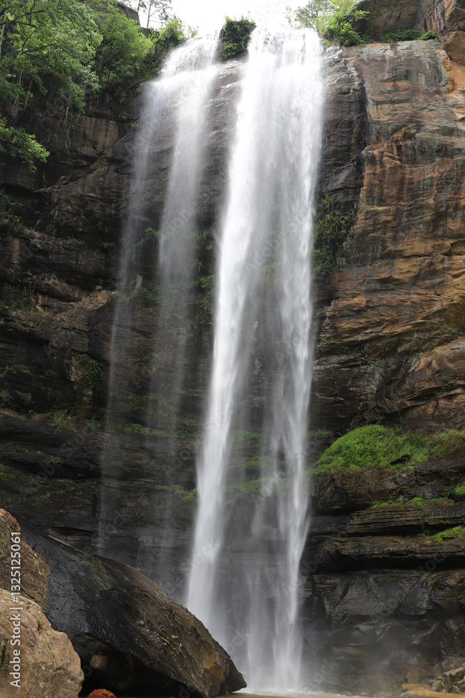 Majestic twin waterfalls cascading down a rugged rock face Majestic twin waterfalls cascading down a rugged rock face