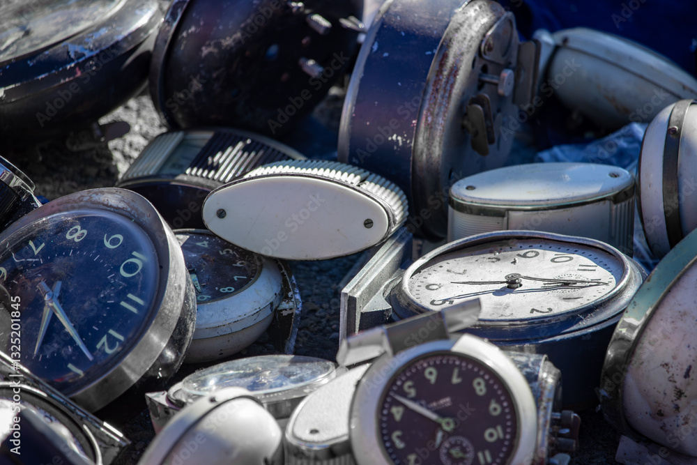 Pile of vintage and antique alarm clocks in various states of rust and disrepair, showcasing the charm and nostalgia of old-fashioned timekeeping devices with their rustic and distressed designs.