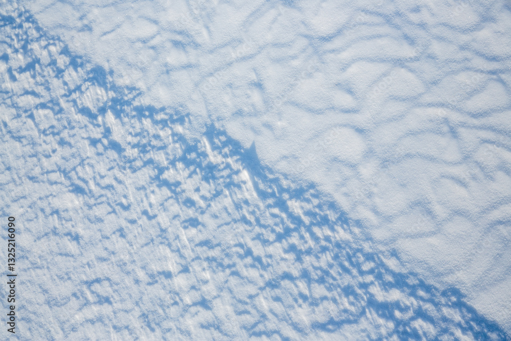 Beautiful winter background with snowy ground. Natural snow texture. Wind sculpted patterns on snow surface.