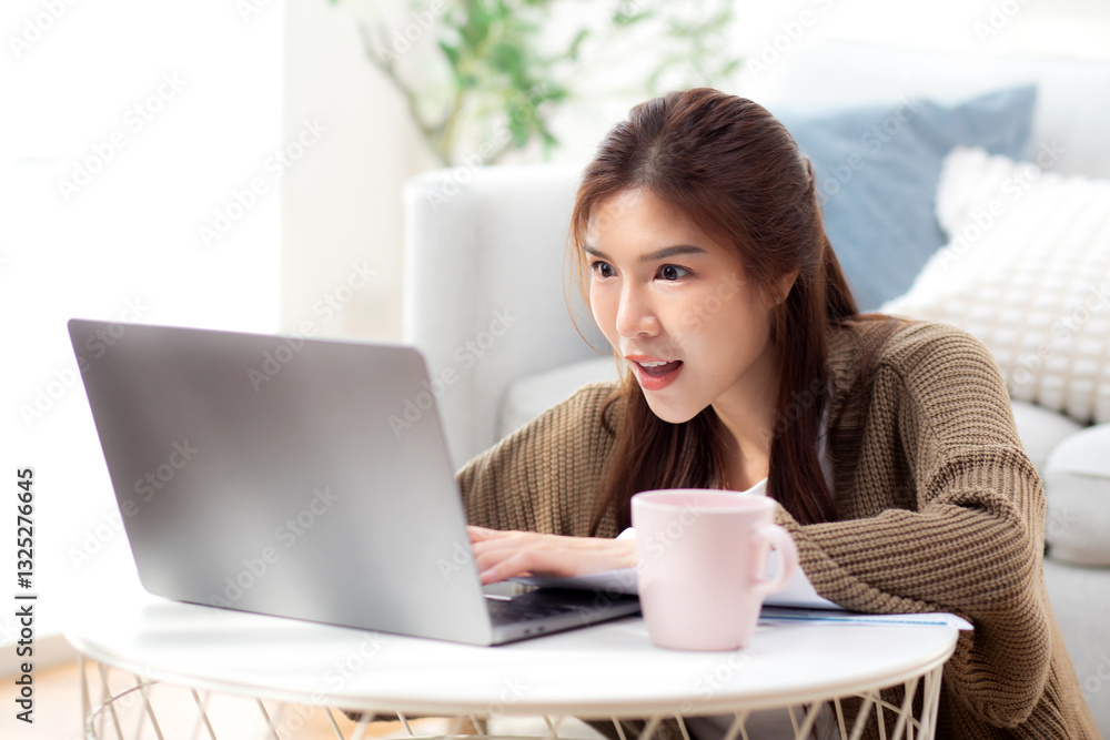 Young asian woman using laptop with surprise in living room at home, woman relaxation with notebook computer or working from home with shock, business browsing email, business and freelance. Young asian woman using laptop with surprise in living room at home, woman relaxation with notebook computer or working from home with shock, business browsing email, business and freelance.