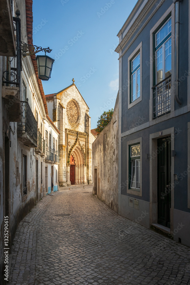 Obraz premium Street view in the historic center of Santarém in Portugal, with the beautiful facade of the church of Nossa Senhora da Graça in the background, illuminated by the sun.