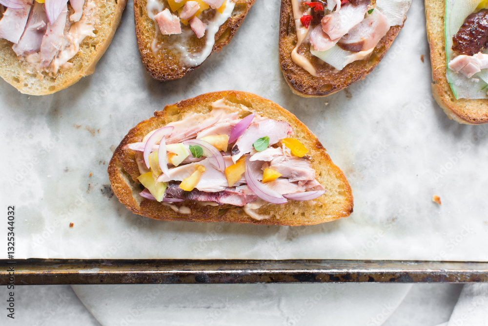 Overhead view of open sandwiches with chicken yellow tomatoes and peppers, top view of sandwich appetizer on a marble background Overhead view of open sandwiches with chicken yellow tomatoes and peppers, top view of sandwich appetizer on a marble background