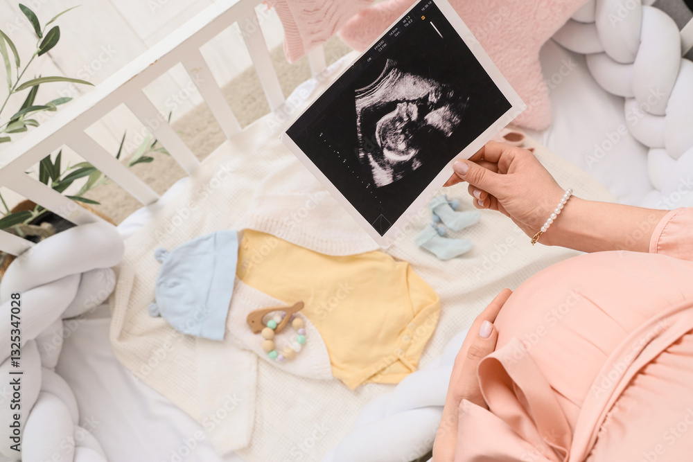 Pregnant woman with sonogram image and baby clothes in crib, top view Pregnant woman with sonogram image and baby clothes in crib, top view
