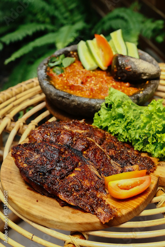 Indonesian's Food. Grilled gourami or Gurame bakar with sambal tomat, slices of cucumber, chilli and lettuce. Selective Focus