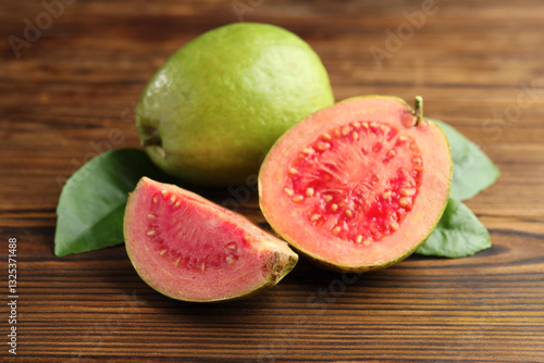 Fototapeta Naklejka Na Ścianę i Meble -  Fresh cut and whole guava fruits with leaves on wooden table, closeup