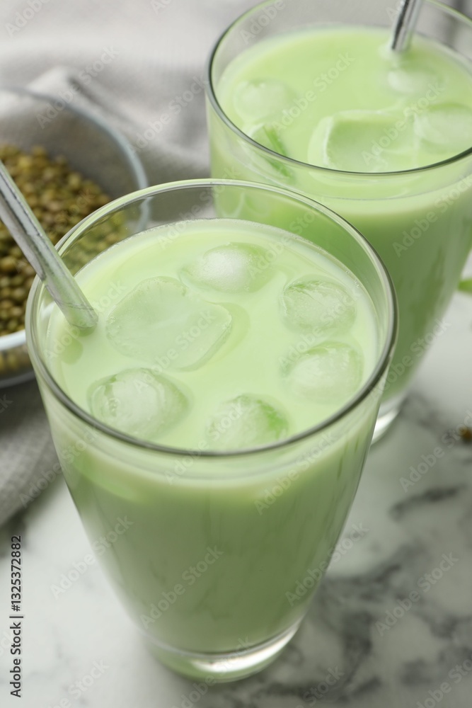 Fresh mung bean juice in glasses and seeds on white marble table, closeup Fresh mung bean juice in glasses and seeds on white marble table, closeup