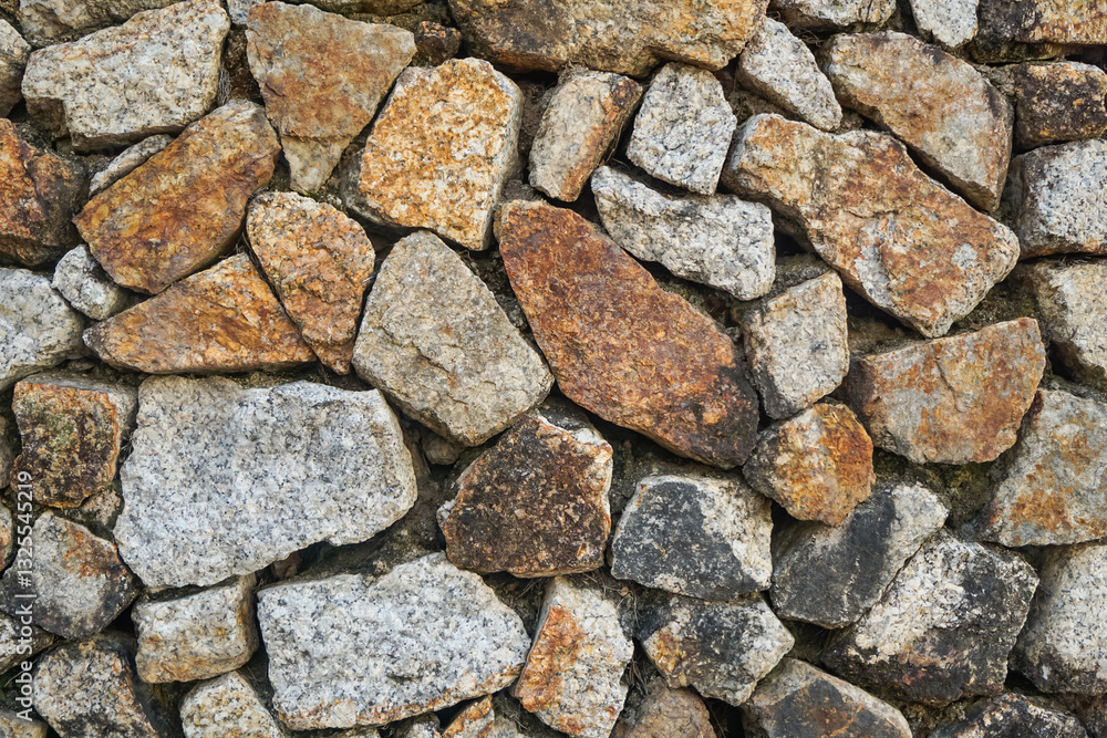 A surface of interlocking stones creating a rustic wall with natural and uneven textures. A surface of interlocking stones creating a rustic wall with natural and uneven textures.