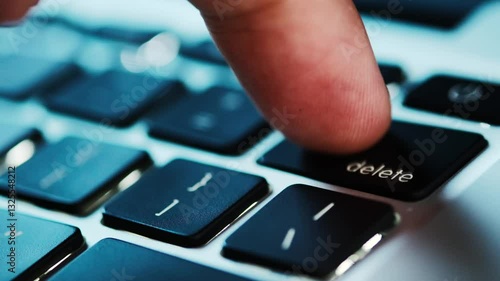Finger of the computer user, he presses the delete button on the computer keyboard	