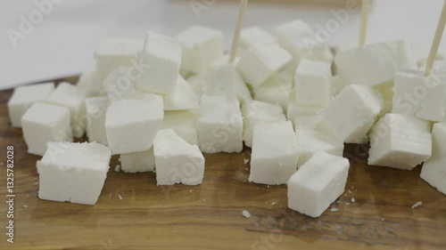 Fresh fetta cheese cubic pieces on a wooden board close up shot