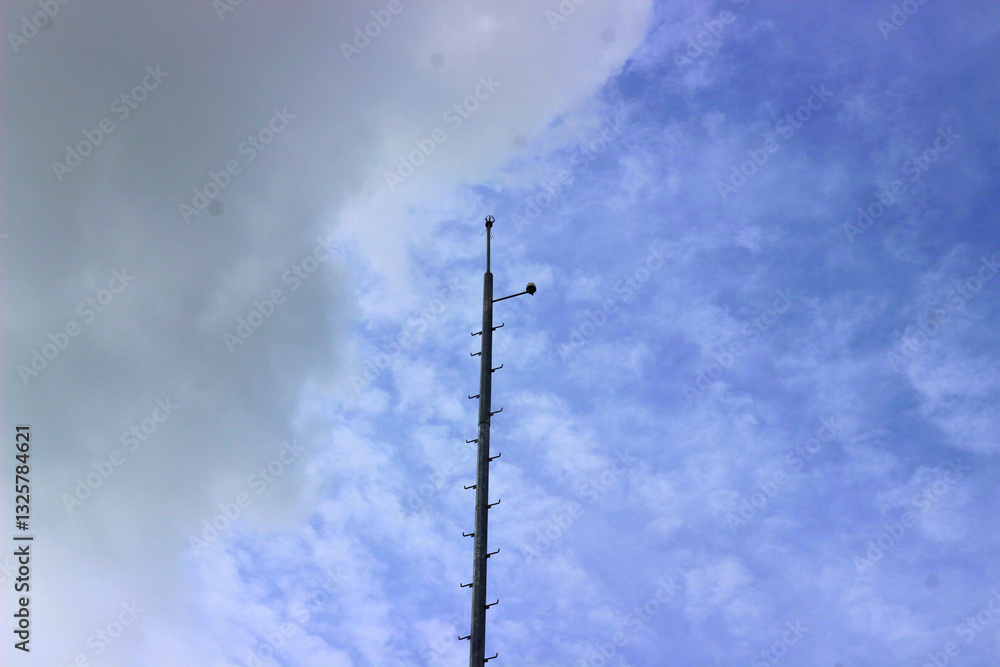 A tall metal pole with ladder rungs reaching towards the cloudy blue sky. Minimalist industrial structure, possibly a telecommunications or surveillance tower, captured from a low-angle perspective.
A tall metal pole with ladder rungs reaching towards the cloudy blue sky. Minimalist industrial structure, possibly a telecommunications or surveillance tower, captured from a low-angle perspective.
