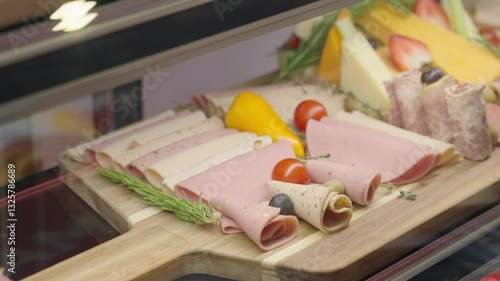 Meat ham assortment on wooden board. Slices of ham decorated with vegetables