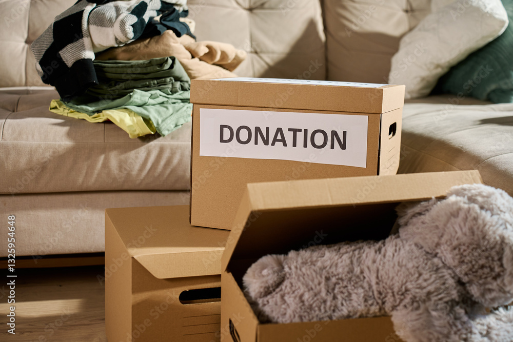 Donation boxes filled with clothes and stuffed toy on couch. Charity and community aid concept